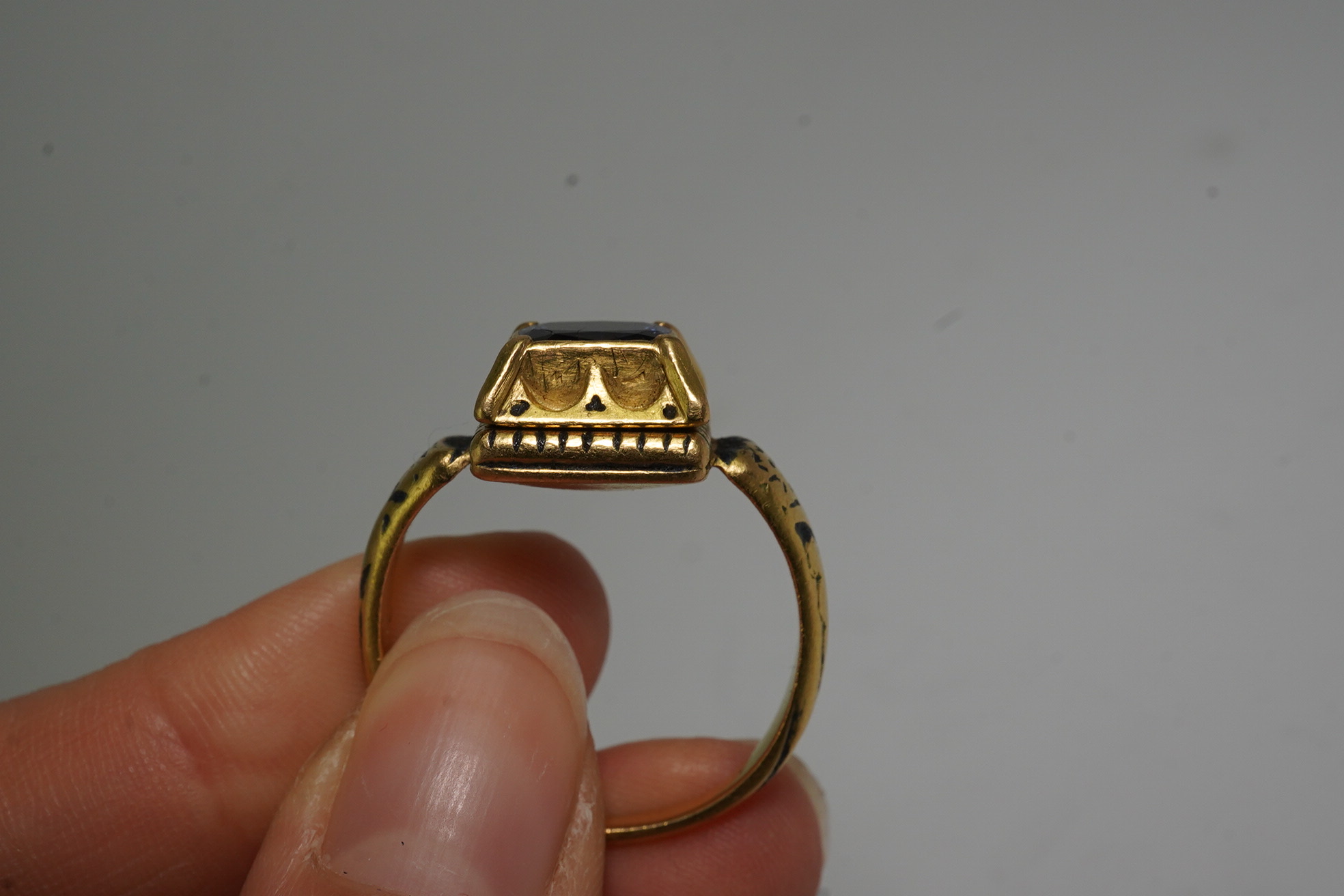 An antique high carat gold, black enamel and collet set cushion cut sapphire set 'poison' ring